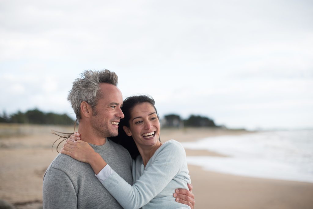 smiling couple on beach, retirement, people hugging, future, positive, happy