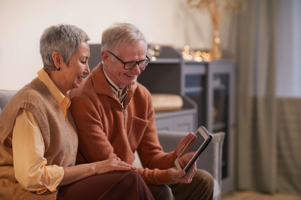 Financial wellbeing, happy couple, sitting on sofa, using ipad, looking at finances