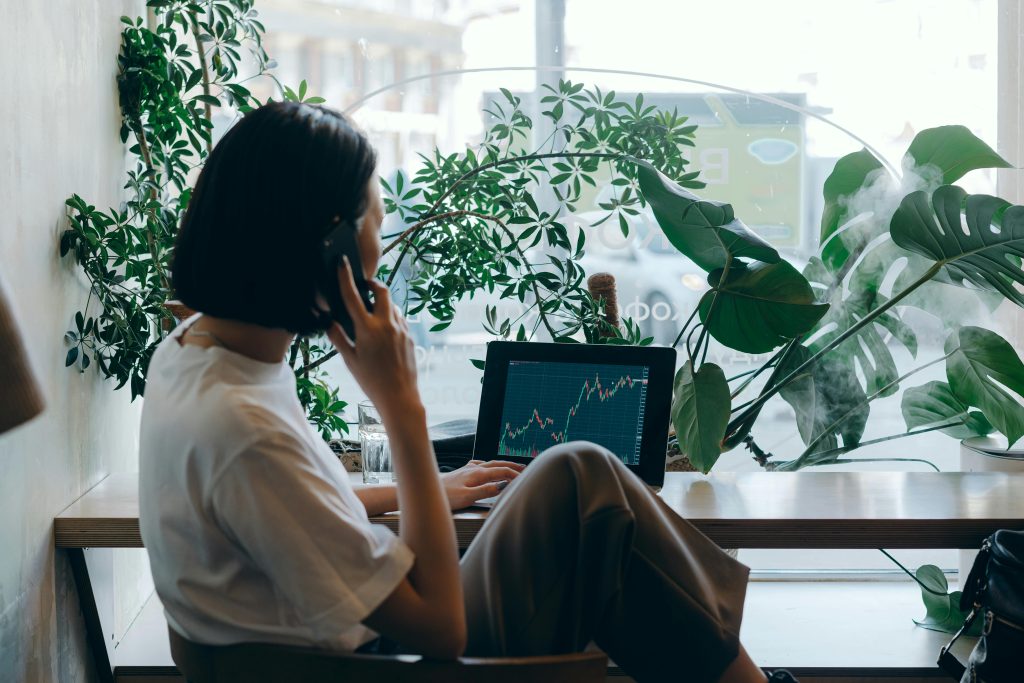 Individual looking at their investment portfolio on their laptop whilst on the phone