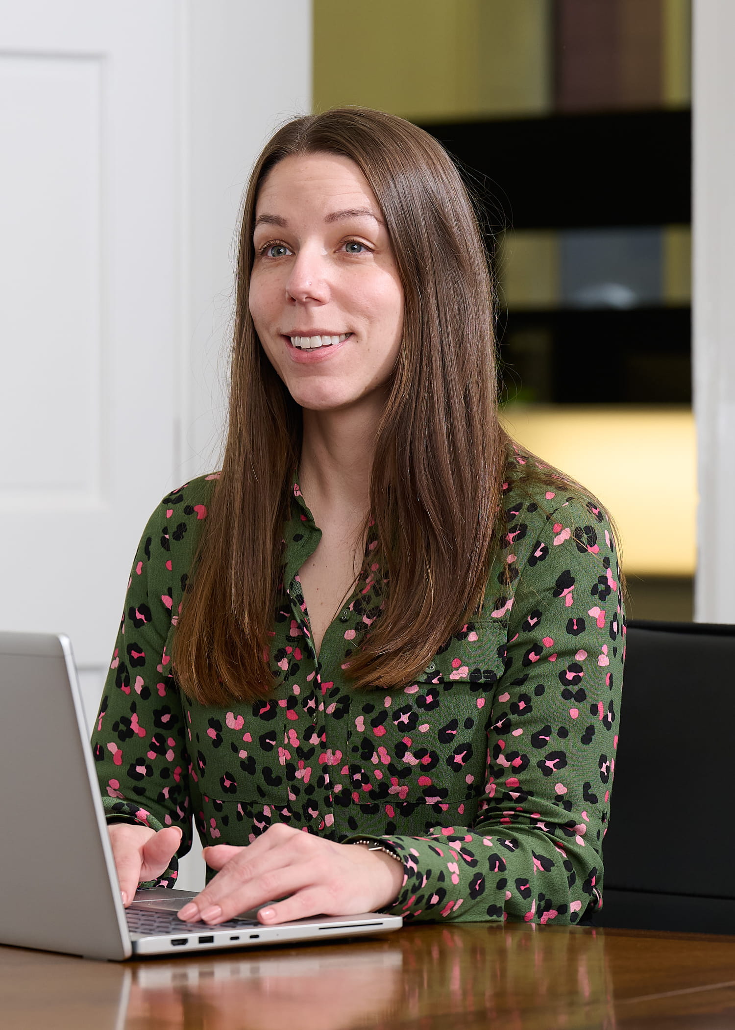 An image of Laura Cowling sitting at a desk with a laptop and smiling.