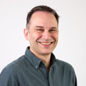 An image of David Neely wearing a shirt and smiling at the camera.