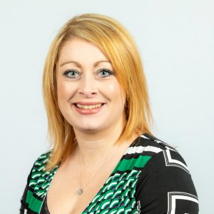 An image of Debbie Connolly wearing a black and green top. She is smiling at the camera.