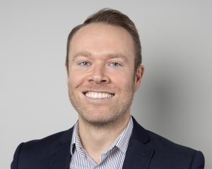 An image of Alan Turner wearing a black suit jacket and smiling at the camera.