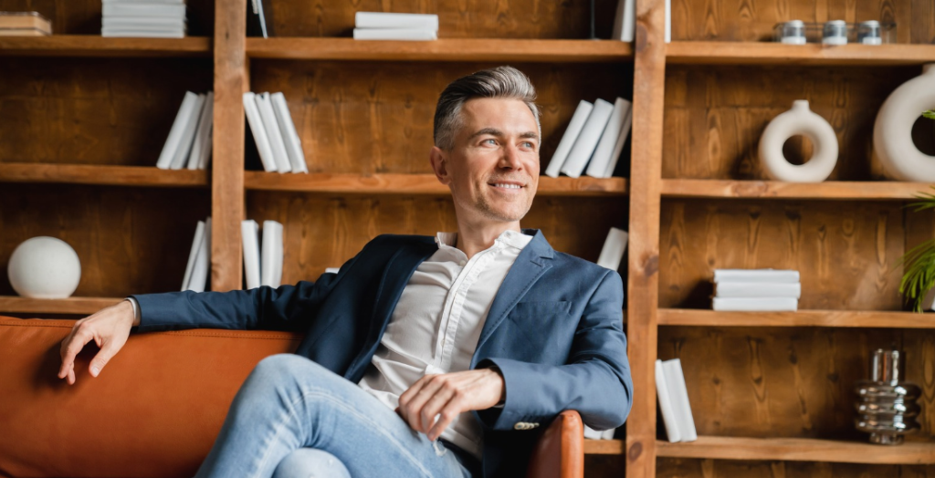 An image of a man sitting on a sofa and smiling at the window.